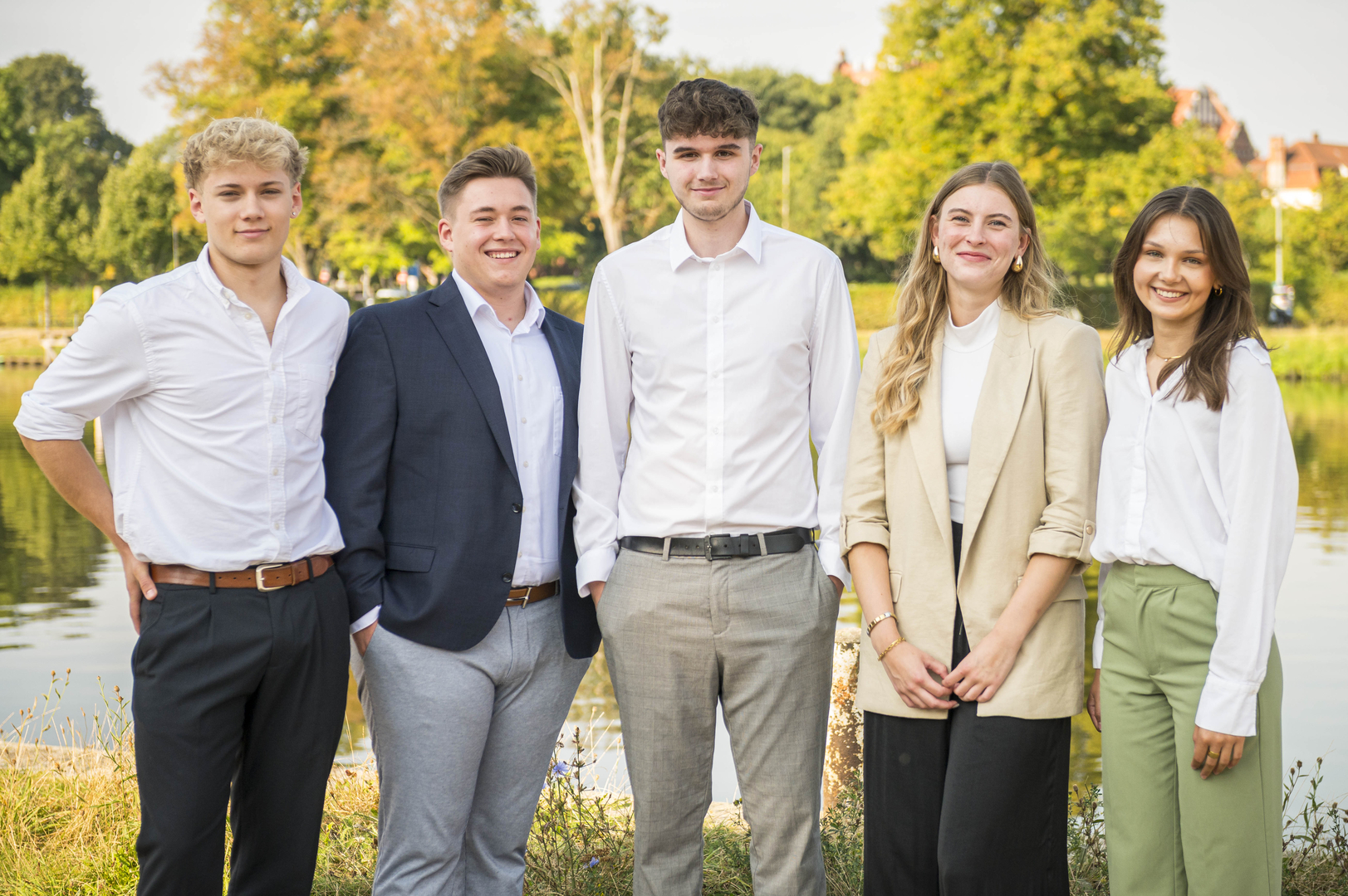 Die TRAVE bildet Immobilienkaufleute aus Eine Gruppe von Auszubildenden schaut in die Kamera: Drei junge Männer und zwei junge Frauen aus verschiedenen Ausbildungsjahren stehen am Ufer der Kanaltrave.