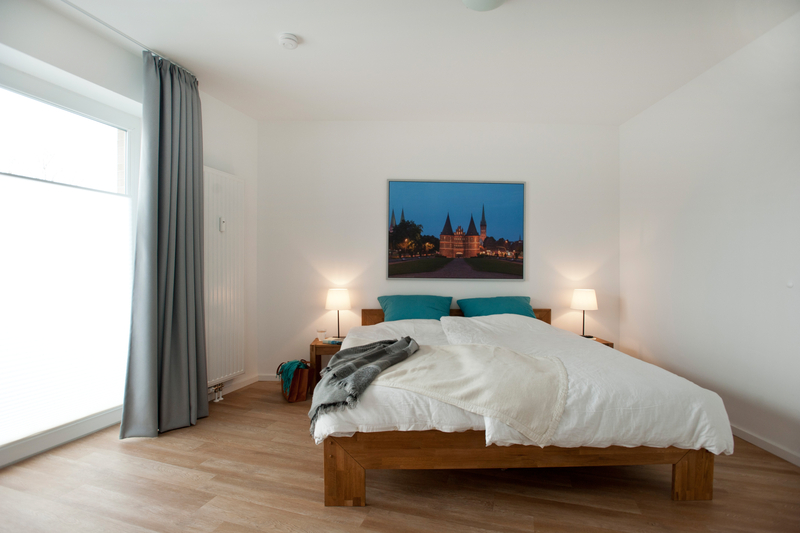 Doppelbett aus Holz, Nachttische mit Nachttischlampen.