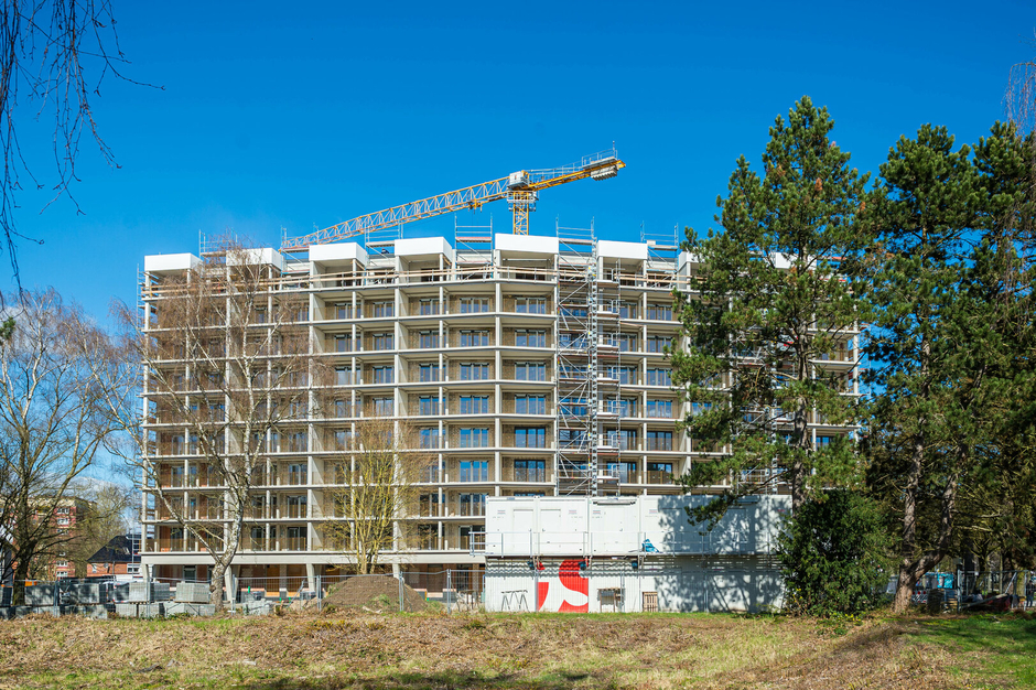 Ein Hochhaus wird renoviert. Man sieht die Baustelle und einen Kran.