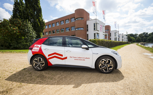 Ein Elektroauto mit dem TRAVE-Design vor dem Gebäude der TRAVE auf der Seite der Kanal-Trave (Fluß). Ein Elektroauto mit dem TRAVE-Design vor dem Gebäude der TRAVE auf der Seite der Kanal-Trave (Fluß).